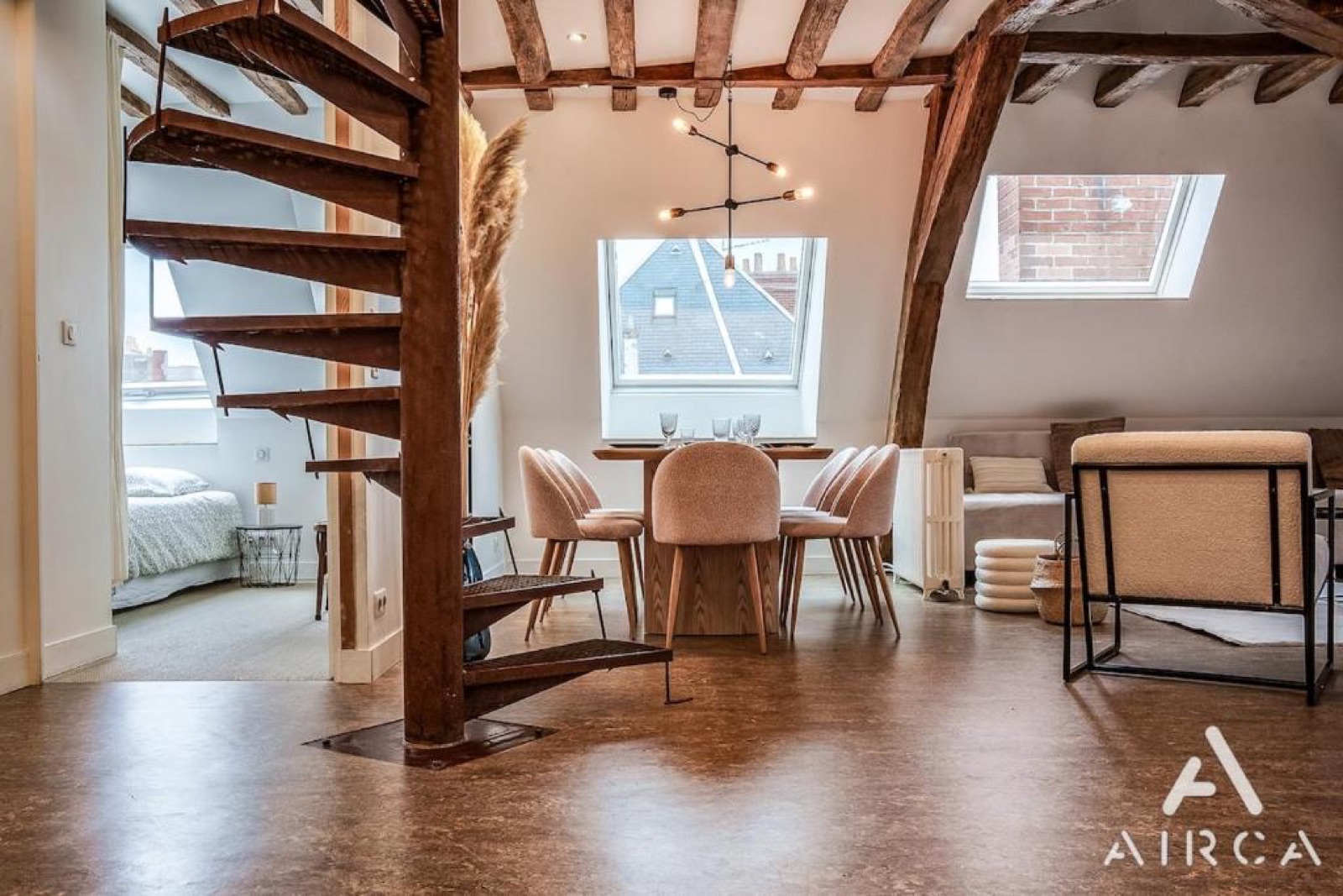 Séjour du Duplex 55 avec poutres apparentes et escalier en colimaçon